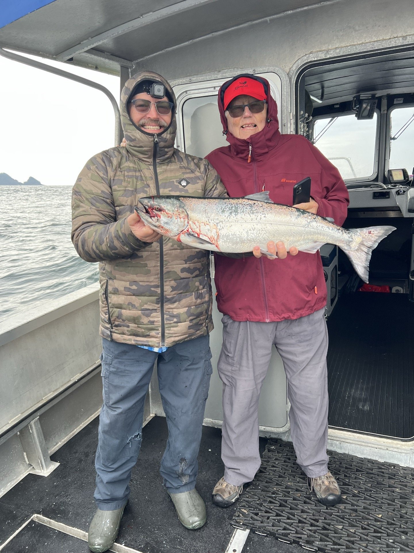 Craig Carson and his dad holding a salmon on a fishing boat