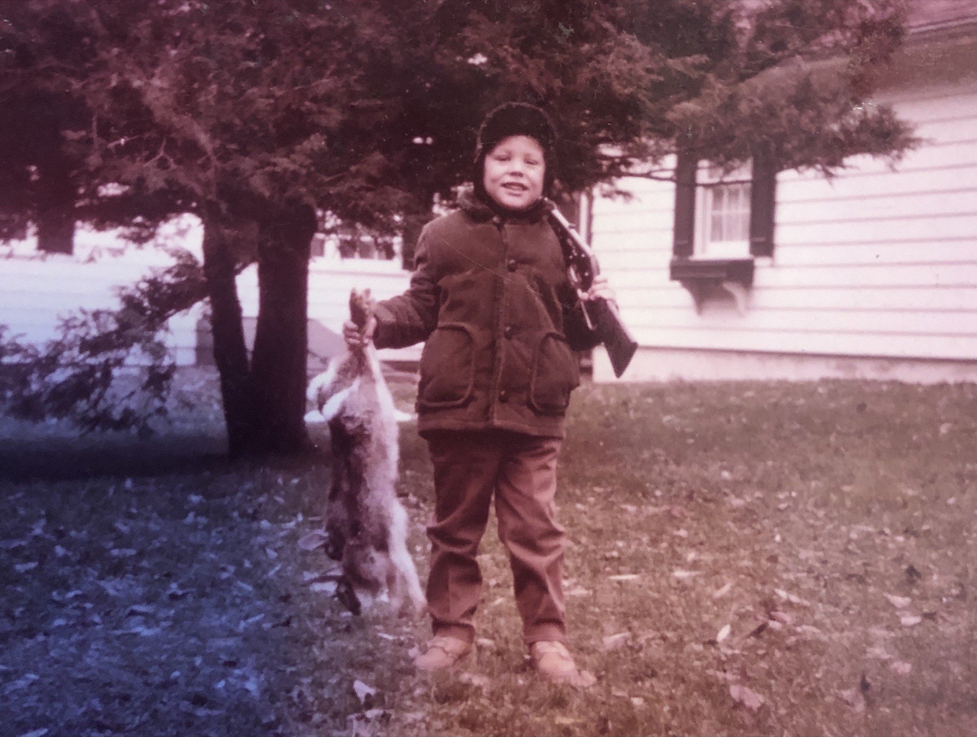 Young Craig Carson with two rabbits and a gun over his shoulder